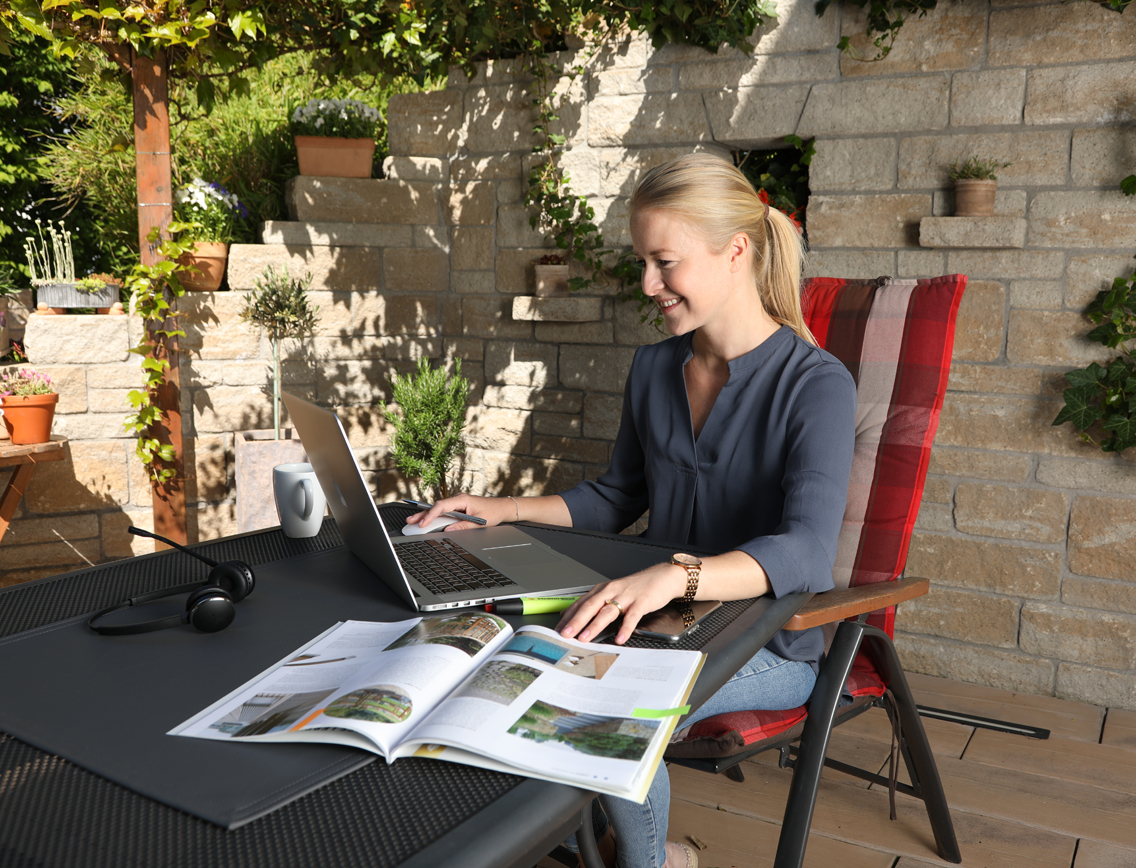 Eine Frau sitzt an einem Arbeitsplatz auf der Terrasse