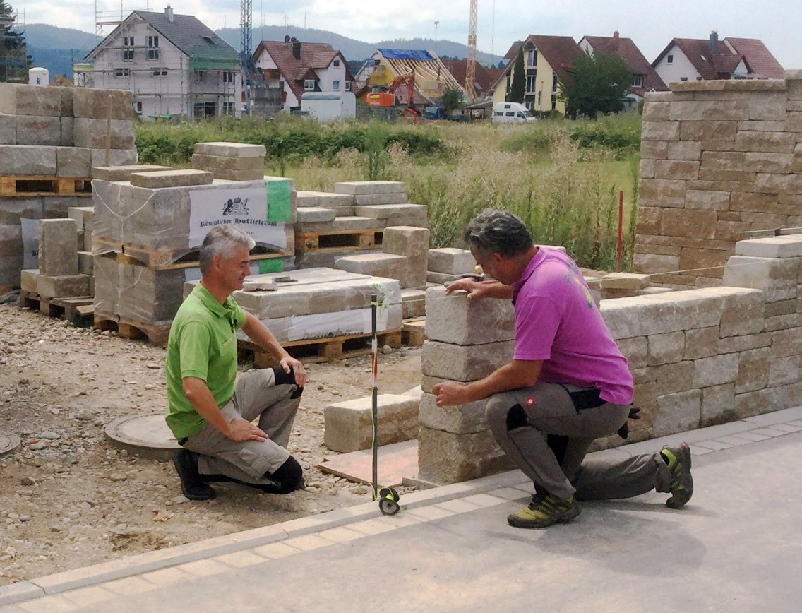 Zwei Männer errichten eine Mauer